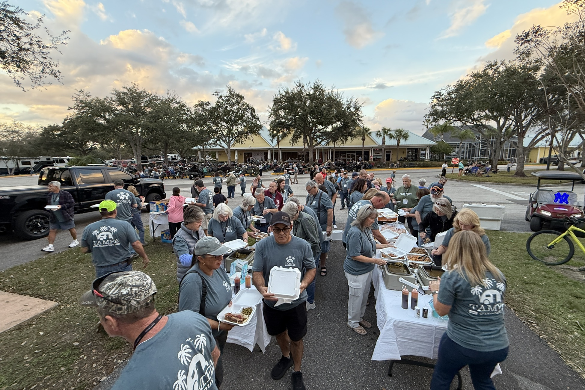 Campout attendees in Tampa Campout shirts going through the dinner line at sunset